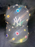Black baseball cap with colorful gemstones and 'NY' logo on a dark background